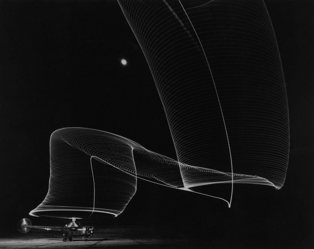 Slinky-like light pattern in the blackness of a moonlit sky produced by a time-exposure of the light-tipped rotor blades of a grounded helicopter as it takes off, 1949.